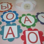 Flowers made of colored paper with large cards with vowels and Y